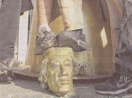 Personen stehen auf dem Kopf einer niedergerissenen Gaddafi-Statue