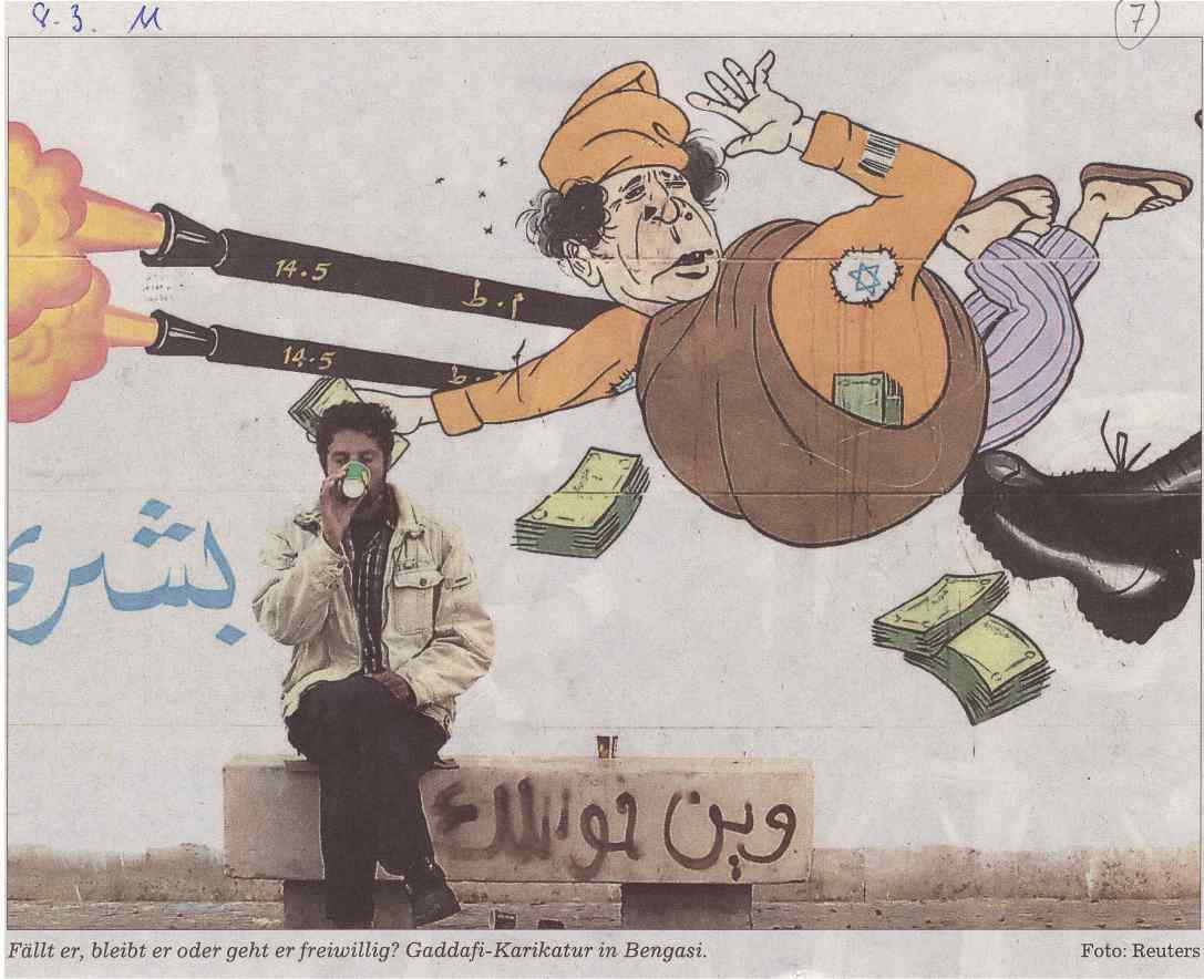 Kaffee trinkender Mann vor Karikatur in Bengasi. Diese Zeigt Gaddafi durch die Luft fliegend. Er wird von einem Fuss getreten und von 2 Raketen beschossen. Pikant: Auf einer Schulter trägt er einen Davidsstern